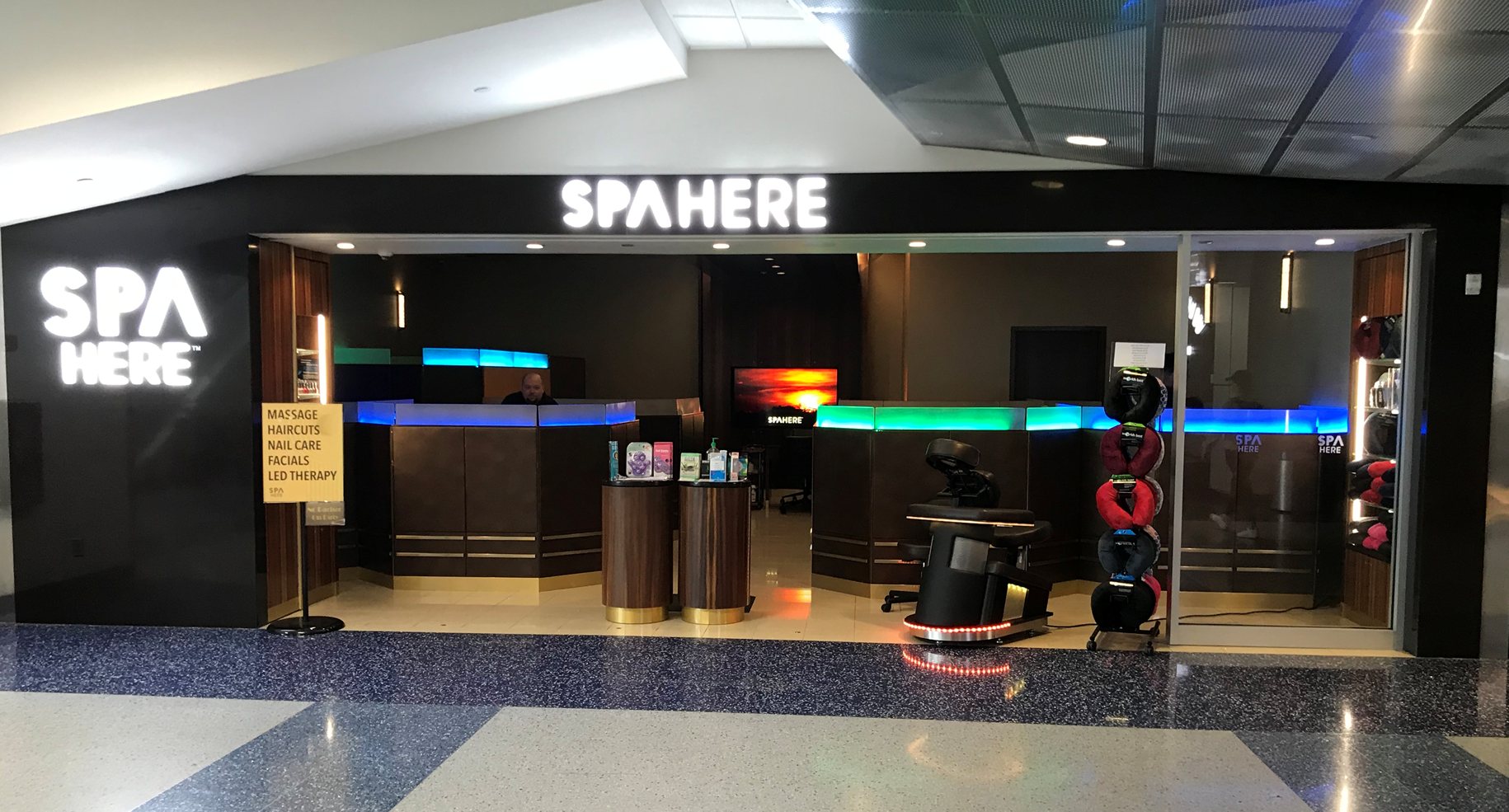 The Spa Here storefront at DFW Terminal C, the wordmark lit above the reception desk